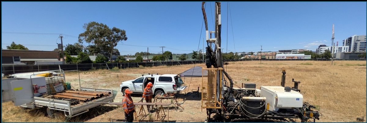 Drill rig and support vehicles on brownfield site — urban apartment development investigation